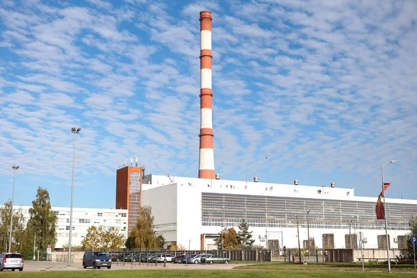 Large, tall electricity thermal power plant red, white color chimney building factory. Photo taken on a warm overcast autumnd ay with blue sky and white clouds.