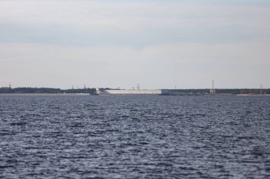 Large river view with large seawall, dam in background. Photo taken on a warm autumn day. Overcast, cloudy weather.