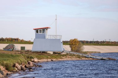 Landscape view with river and small lifeguard house on the left side. Cloudy weather.