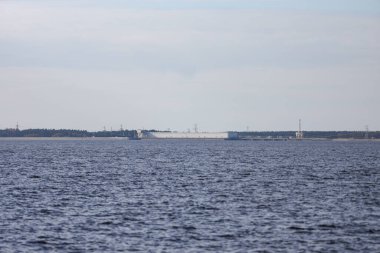 Large river view with large seawall, dam in background. Photo taken on a warm autumn day. Overcast, cloudy weather.