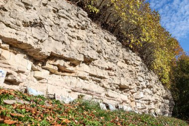 Beautiful natural landscape view of dolomite cliff wall exposure. Photo taken on a warm sunny autumn day with yellow trees.