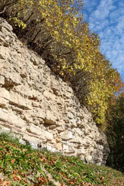 Beautiful natural landscape view of dolomite cliff wall exposure. Photo taken on a warm sunny autumn day with yellow trees.