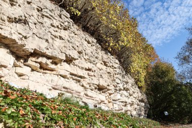 Beautiful natural landscape view of dolomite cliff wall exposure. Photo taken on a warm sunny autumn day with yellow trees.