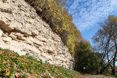 Beautiful natural landscape view of dolomite cliff wall exposure. Photo taken on a warm sunny autumn day with yellow trees.