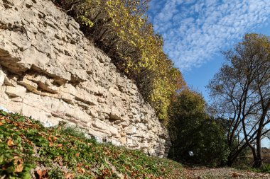 Beautiful natural landscape view of dolomite cliff wall exposure. Photo taken on a warm sunny autumn day with yellow trees.