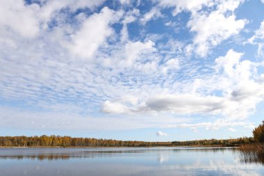 Ağaçlarla, gölle ve bulutlu gökyüzüyle güzel bir sonbahar manzarası. Fotoğraf Ekim 'de çekildi.