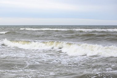 Orta ölçekli baltık deniz dalgaları beyaz kabarcıklar. Fotoğraf sıcak, bulutlu bir sonbahar gününde çekildi..