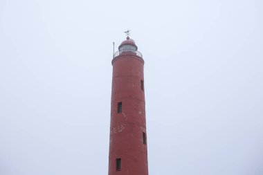 Letonya 'da Baltık Denizi yakınlarında Akmensraga feneri denilen eski bir deniz feneri. Fotoğraf, bulutlu bir sonbahar gününde çekildi..