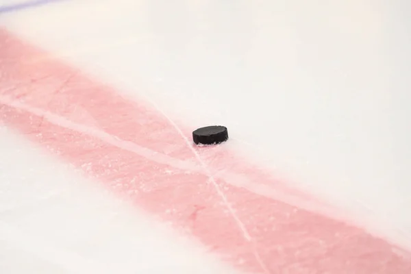 Ice Hockey rink details close up ice texture with ice hockey puck. Photo taken inside ice hockey rink before game warmup.