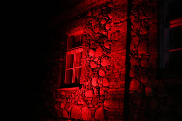 Caddenin yanındaki eski tuğladan ev kırmızı beyaz Letonya bayrak ışıklarıyla süslenmiş. Fotoğraf sıcak bir sonbahar akşamında çekildi..