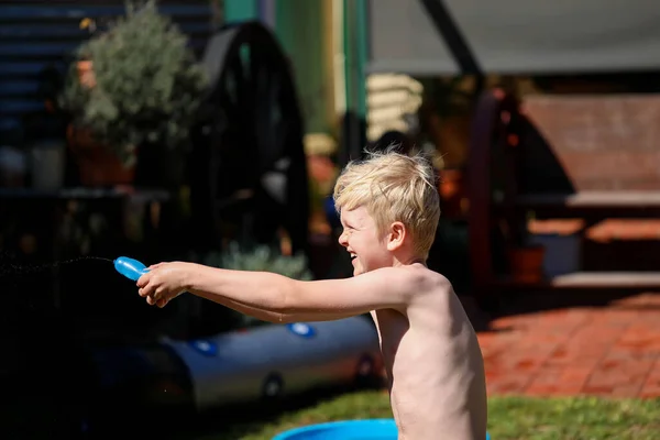 Aussie kids enjoying backyard water fight in summer