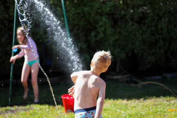 Aussie kids enjoying backyard water fight in summer