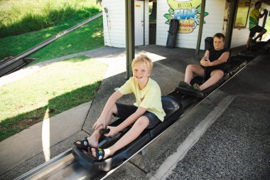 Coffs Harbour, NSW Avustralya - 17 Mart 2022: Çocuklar Büyük Muz eğlence parkında kızakla geziyorlar