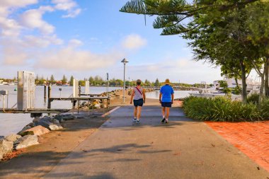 Forster NSW Australia - 13 April 2022: Elderly couple enjoying morning walk at the Forster Marina on Lake Wallis, NSW Australia