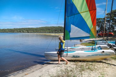 Smith Gölü, NSW Avustralya - 29 Nisan 2022: Çocuklar güneşli bir günde köpüklü kahve kayıkhanesinde yelkencilik dersine katılıyor