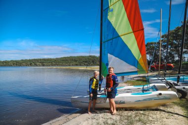 Smith Gölü, NSW Avustralya - 29 Nisan 2022: Çocuklar güneşli bir günde köpüklü kahve kayıkhanesinde yelkencilik dersine katılıyor