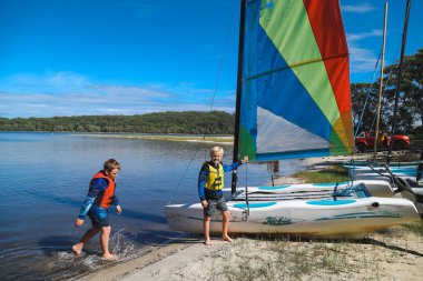 Smith Gölü, NSW Avustralya - 29 Nisan 2022: Çocuklar güneşli bir günde köpüklü kahve kayıkhanesinde yelkencilik dersine katılıyor