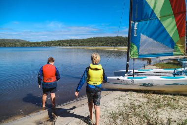 Smith Gölü, NSW Avustralya - 29 Nisan 2022: Çocuklar güneşli bir günde köpüklü kahve kayıkhanesinde yelkencilik dersine katılıyor