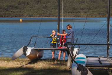 Smith Gölü, NSW Avustralya - 29 Nisan 2022: Çocuklar güneşli bir günde köpüklü kahve kayıkhanesinde yelkencilik dersine katılıyor