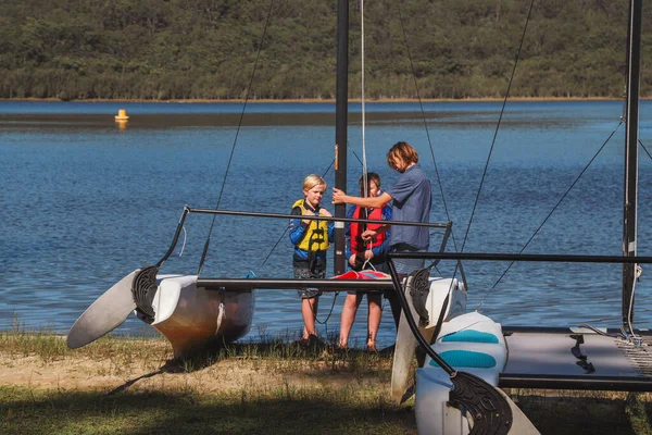 Smith Gölü, NSW Avustralya - 29 Nisan 2022: Çocuklar güneşli bir günde köpüklü kahve kayıkhanesinde yelkencilik dersine katılıyor