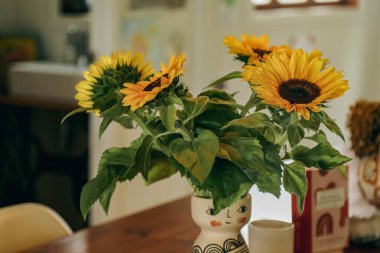 Mutfak masasında bir demet ayçiçeği açar. Ev dekorasyonu..