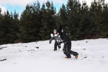 Karlı kış harikalar diyarında oynayan mutlu çocuklar kartopu savaşı yapıyorlar.
