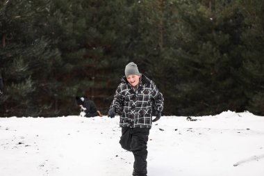 Karlı kış harikalar diyarı kartopu savaşında oynayan genç çocuk.