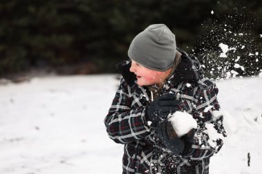 Karlı kış harikalar diyarı kartopu savaşında oynayan genç çocuk.