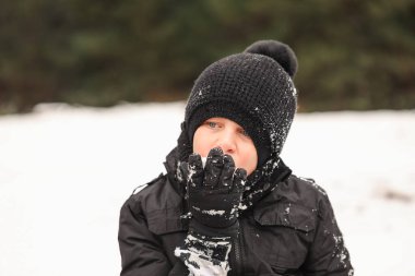 Kış tatilinde kar yiyen genç bir çocuğun portresi.