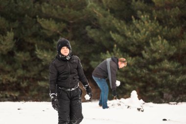 Babasıyla karda oynayıp arka planda kardan adam yapan mutlu çocuk.