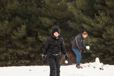 Babasıyla karda oynayıp arka planda kardan adam yapan mutlu çocuk.