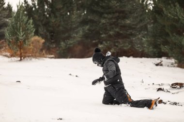 Karlı kış harikalar diyarında kar elbisesi giyen genç bir çocuk