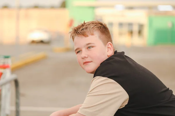 Relaxed preteen boy hanging out in urban car park. Blonde hair blue eyes.