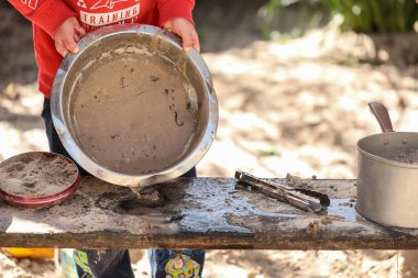 Anaokulundaki çocuklar kum havuzunda oynuyorlar. Anaokulunda çamurlu turtalar yapıyorlar.