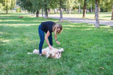Genç bir kadın köpeğiyle dışarıda oynuyor..