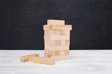 Ahşap bloklar kulesinin yakın görüntüsü. Hassas durumların metaforu. Boyanmamış tuğlalara odaklan. Risk ve planlama stratejisi. Jenga oyunu