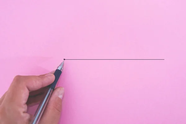 Hand with a pen with an outline to the end point on a pink paper background. Creativity inspiration idea concept