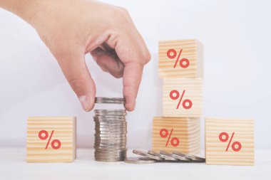 Faiz oranı finansal ve tasarruf kavramı. El, madeni paralar ve yüzde sembolü olan bir yığın içine bozuk para koyuyor..