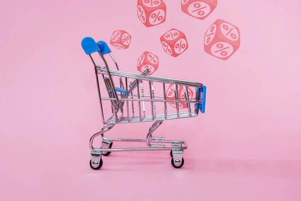 ピンクの背景にキューブ上の赤いパーセント記号と青のショッピングカート 小売と割引の概念 — ストック写真