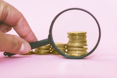 Pembe arka plandaki bir büyüteçten para yığını. Avro paraları.
