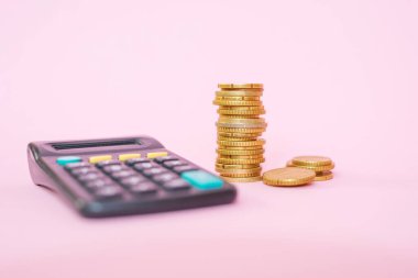 Pembe arka planda bir yığın bozuk para ve hesap makinesi. Avro paraları