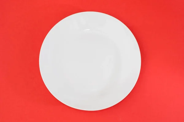 Kırmızı Zemin Üzerinde Boş Beyaz Bir Plaka Yukarıdan Görüntüle — Stok fotoğraf