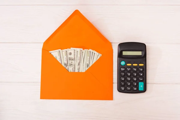 Dollar Einem Orangefarbenen Umschlag Und Einem Taschenrechner Auf Weißem Holzgrund — Stockfoto