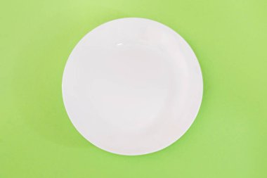 Yeşil arka planda boş beyaz bir plaka. Yukarıdan görünüm.