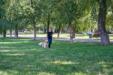 Bir yaz günü kadın köpeğiyle parkta yürür. Uzaktan görüntüle