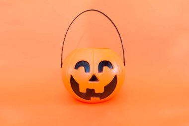 Cadılar Bayramı mevsimleri için turuncu arka planda balkabağı sepeti. Plastik balkabağı, öğürme ya da ikram, mevsimlik kutlama.