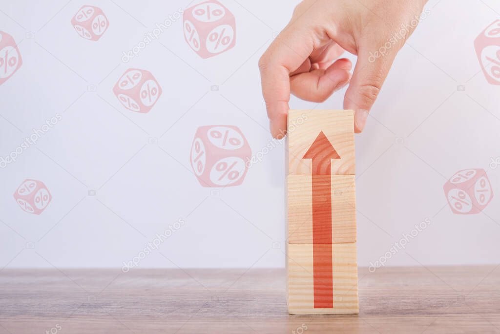 Interest rate financial and mortgage rates concept. Hand putting wood cube block increasing on top with icon percentage symbol and arrow upward direction