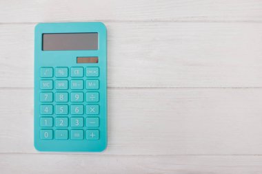 Beyaz ahşap zemin üzerinde kopyalama alanı olan mavi hesap makinesi. Yukarıdan görüntüle.