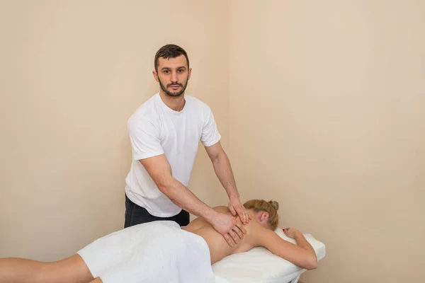 Massaggiatore Massaggiando Schiena Scapole Una Giovane Donna Sdraiata Tavolo Massaggio — Foto Stock