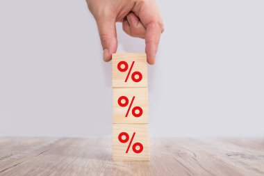 Faiz oranı finansal ve ipotek oranları kavramı. Elle yerleştirilen tahta küp bloğu üste yükseltiliyor ve simge yüzdesi sembolü yukarı doğru gösteriliyor